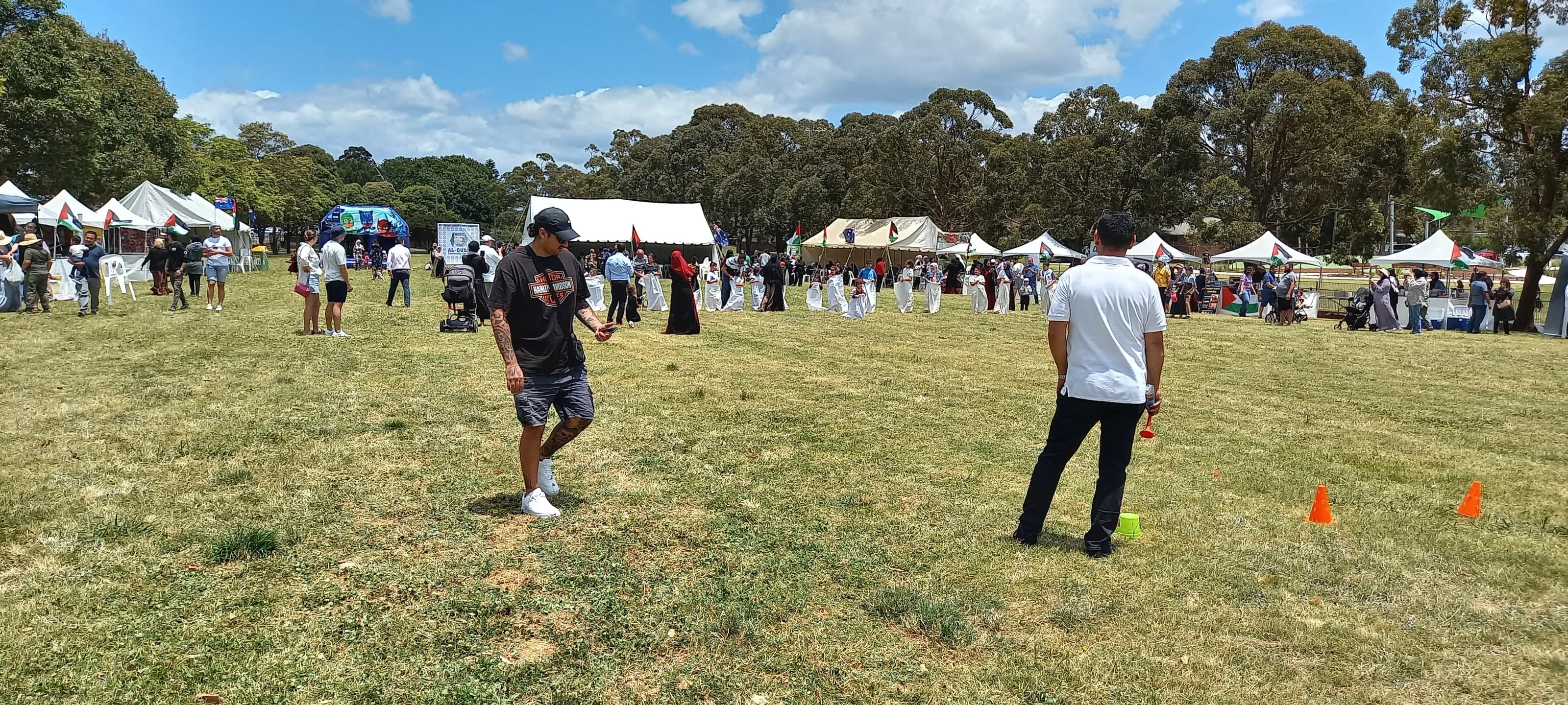 Organisers setting out the course for the sack race, with children in sacks lined up in front of the stalls